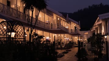 A multi-story hotel with balconies, outdoor seating, and a well-lit entrance.