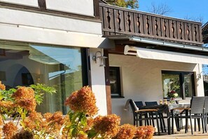 A modern building with a balcony, outdoor seating, and a window with a view. - Holiday home with 4 bedrooms (Garmisch-Partenkirchen)
