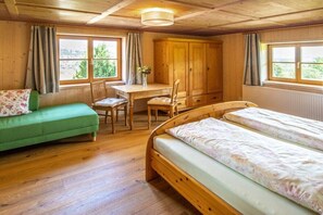 Ein Zimmer mit einem Bett, einem Schreibtisch, einem Sessel und einer Couch.