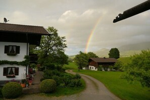 Ländliche Landschaft mit einem Haus, einem Pfad und einem Regenbogen.