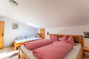 Ein Schlafzimmer mit zwei Betten, einem Oberlicht, Holzmöbeln und einem kleinen Fenster.