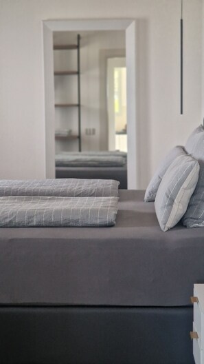 A modern bedroom with a bed, pillows, and a view into an adjacent room. - Villa Vinomare in Lunigiana. Infinity hot tub with sea view (Toscana)
