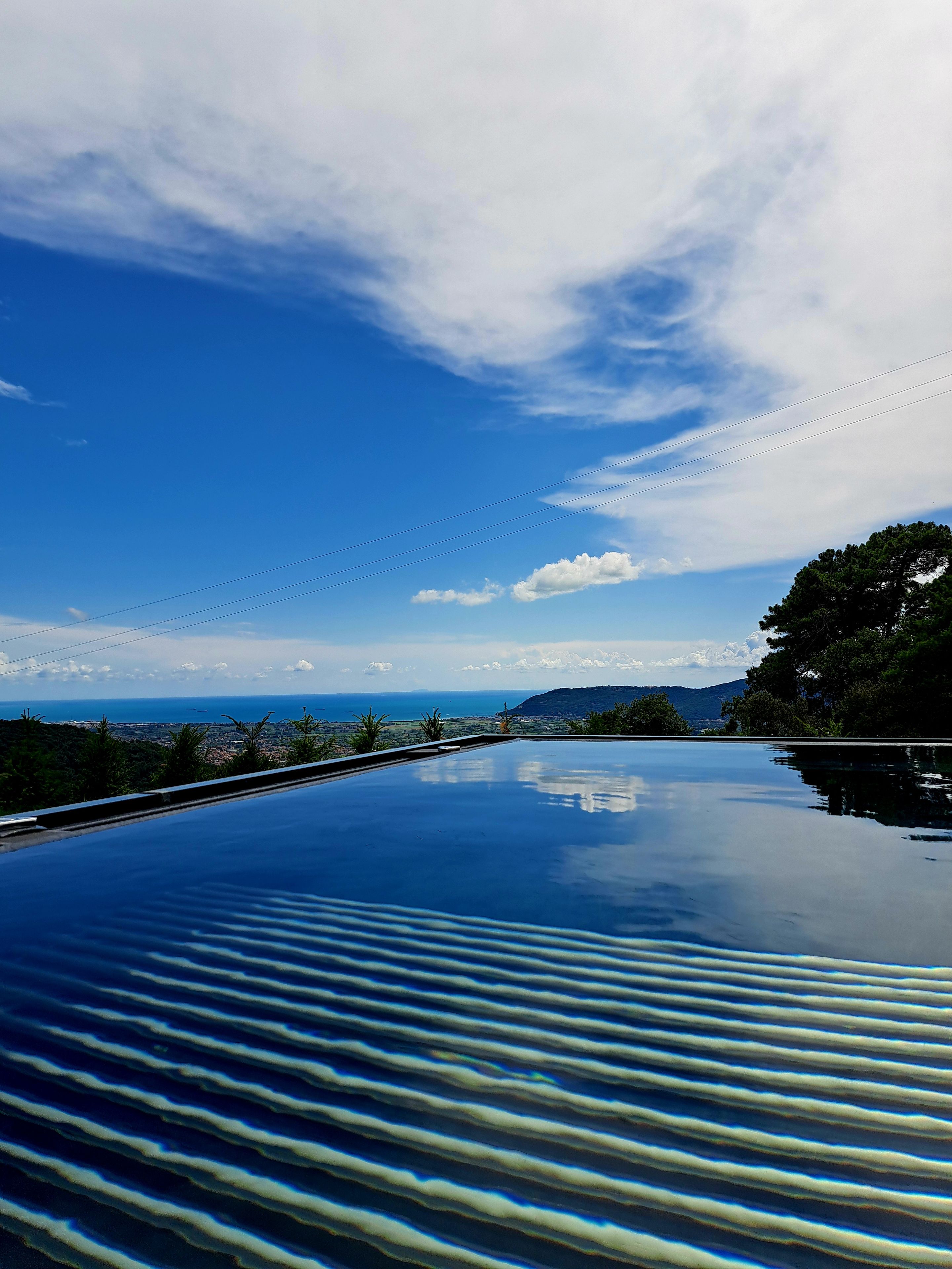 On aperçoit clairement une piscine, avec en arrière-plan un paysage lointain comprenant une étendue d’eau et des montagnes.