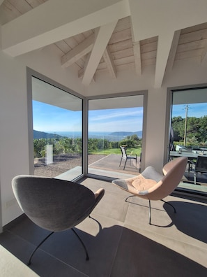 A modern interior with a large glass door leading to an outdoor patio area. - Villa Vinomare in Lunigiana. Infinity hot tub with sea view (Toscana)