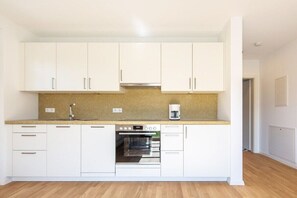 Een moderne keuken met witte kasten, een ingebouwde oven en een koffiezetapparaat.
