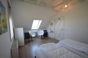 A bedroom with a sloped ceiling, a skylight, a bed, a desk, and two chairs. - Holiday home with 2 bedrooms (Oostkapelle)