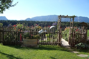 A wooden fence with a gate, a potted plant, and a pathway leading to a wooden structure. - Holzner "Holidays like on a farm" (Inzell)