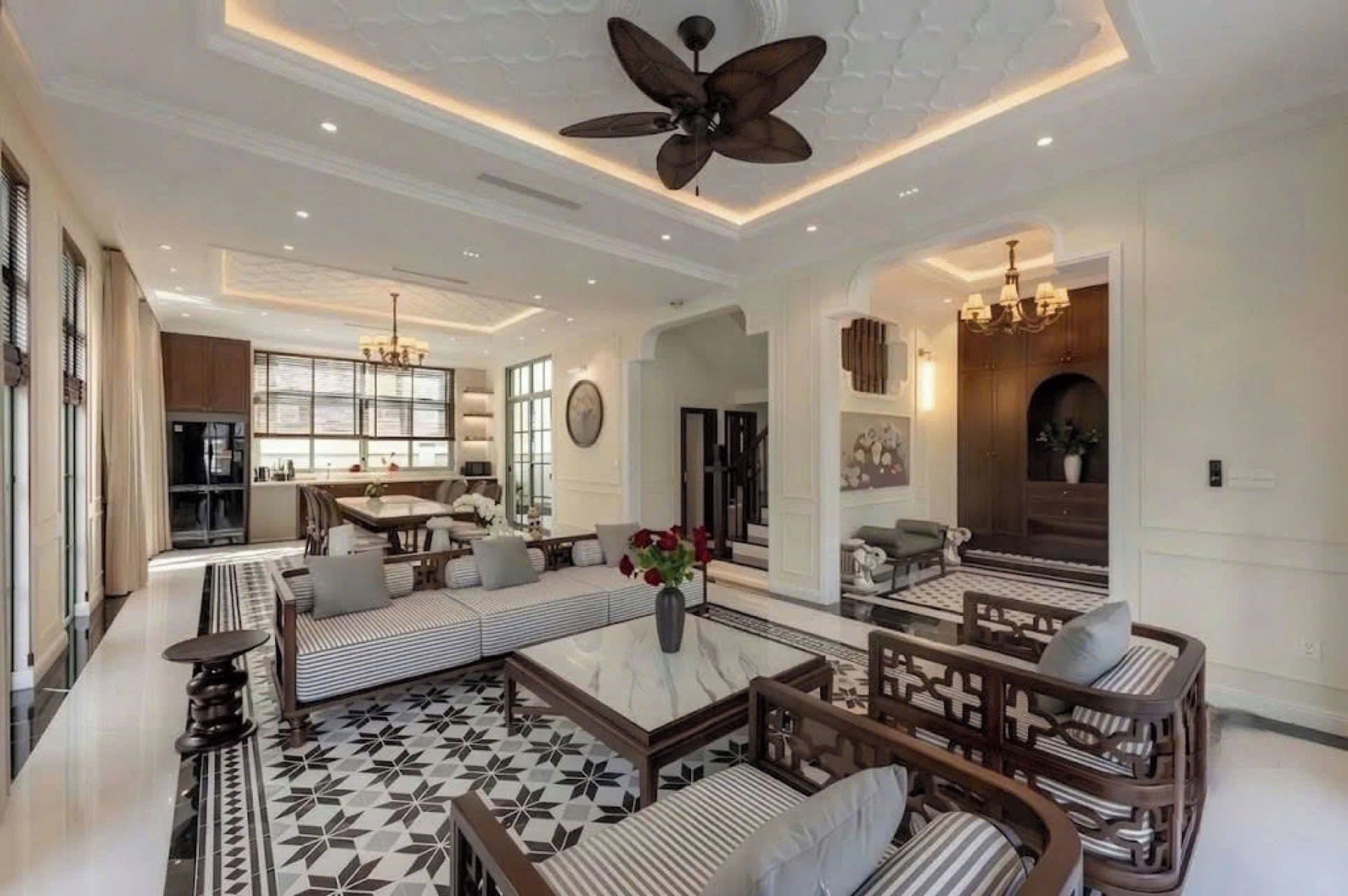 A spacious living room with a high ceiling, a central seating area with sofas and a coffee table, and a kitchen area in the background.