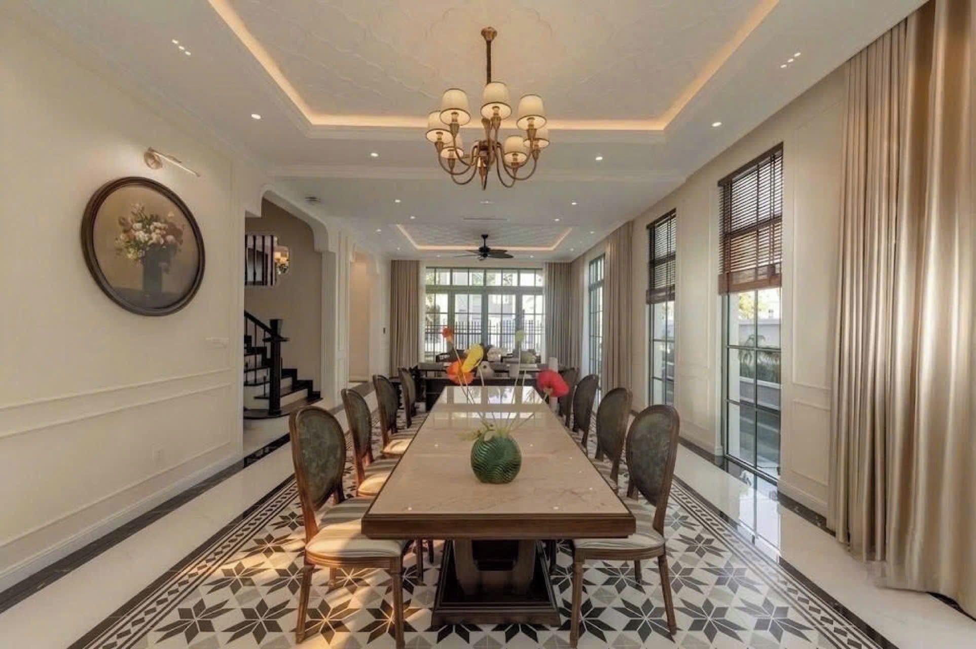 A spacious dining room with a long table, chairs, and a chandelier.