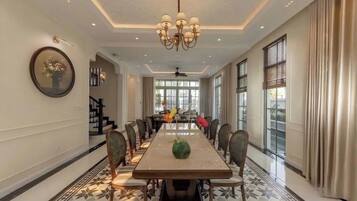 A spacious dining room with a long table, chairs, and a chandelier.
