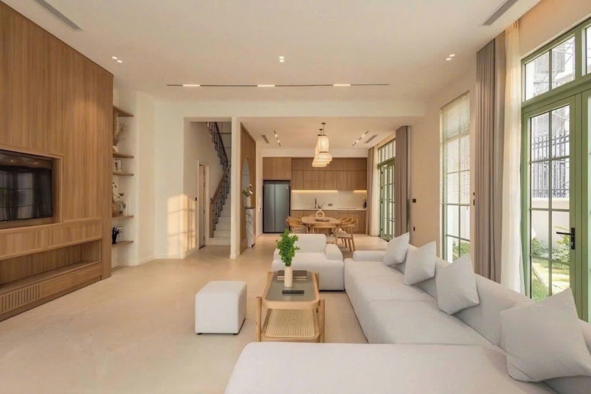 Una sala moderna con sofá, reposapiés y mesa de centro. Una escalera conduce a una zona de cocina.