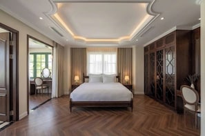 Un dormitorio amplio con una cama grande, piso de madera y vista a un área verde exterior.