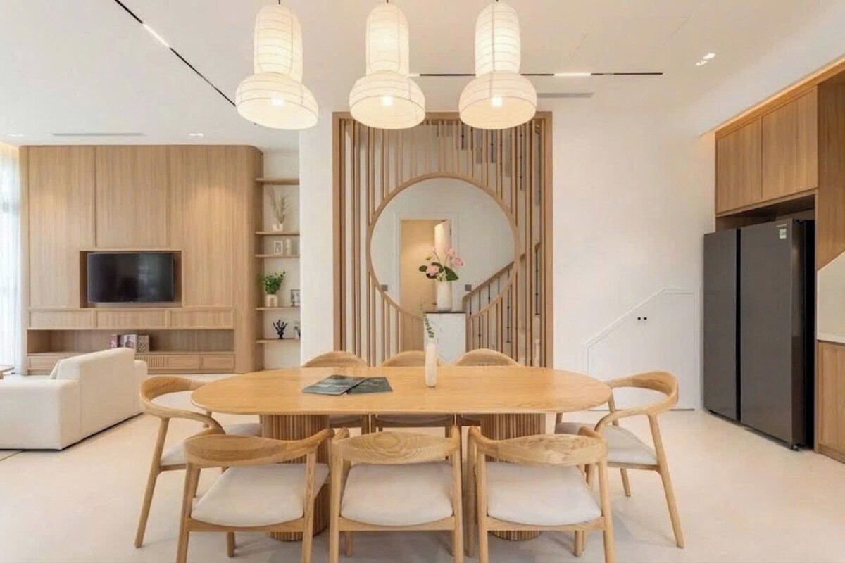 Un comedor moderno con una mesa redonda, seis sillas y un espejo grande sobre la mesa.