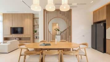 Un comedor moderno con una mesa redonda, seis sillas y un espejo grande sobre la mesa.