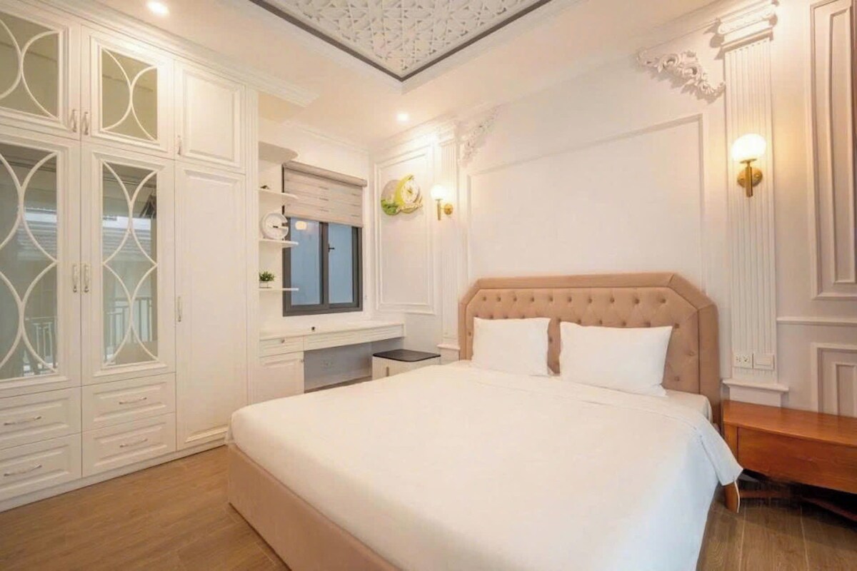 Un dormitorio con una cama grande, un aparador, un espejo y una ventana.