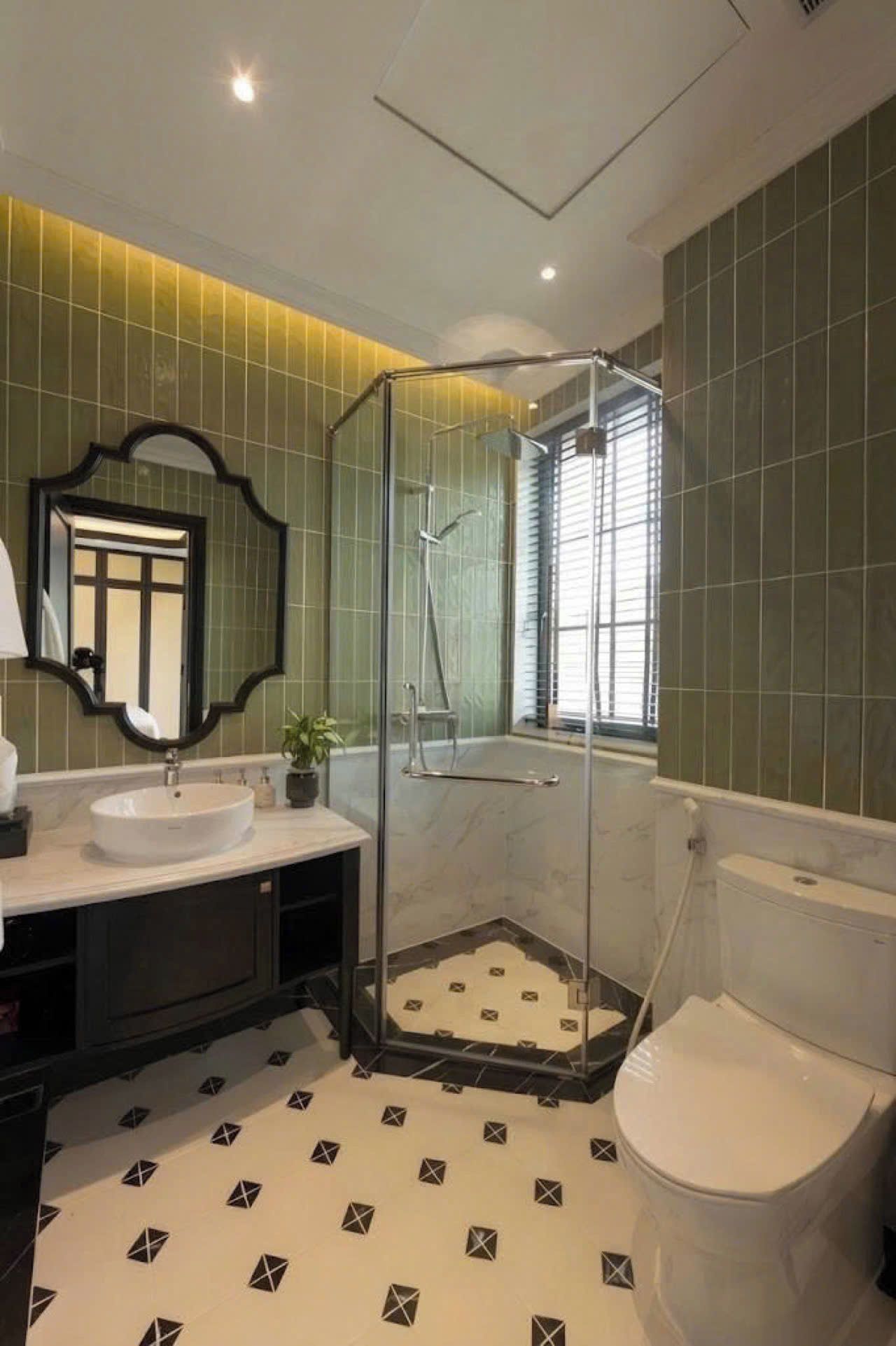 Un baño con ducha de vidrio, lavamanos blanco y retrete.