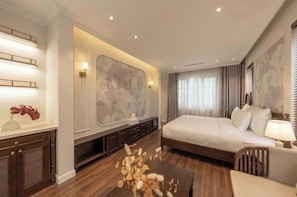 Habitación de hotel con una cama grande, un escritorio con lámpara, un jarrón decorativo y una obra de arte colgada en la pared.