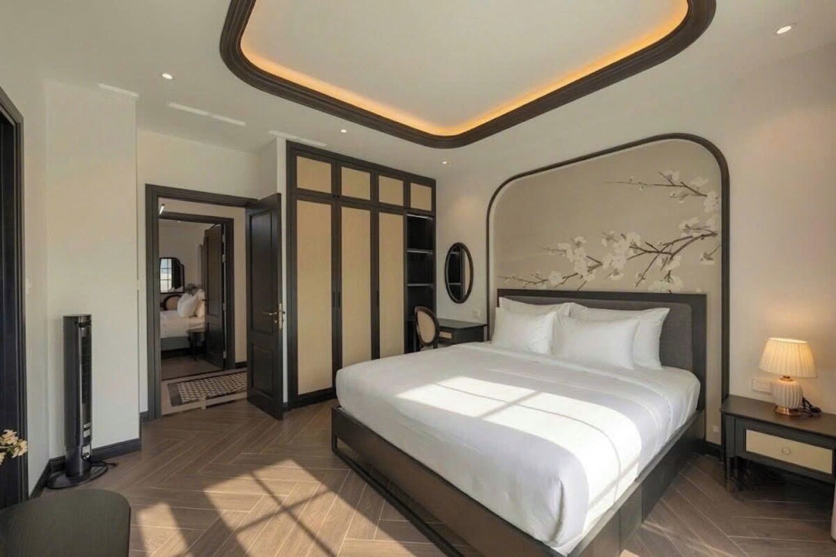 Una habitación de hotel moderna con una cama grande, una mesita de noche, un espejo y un adornado en la pared.