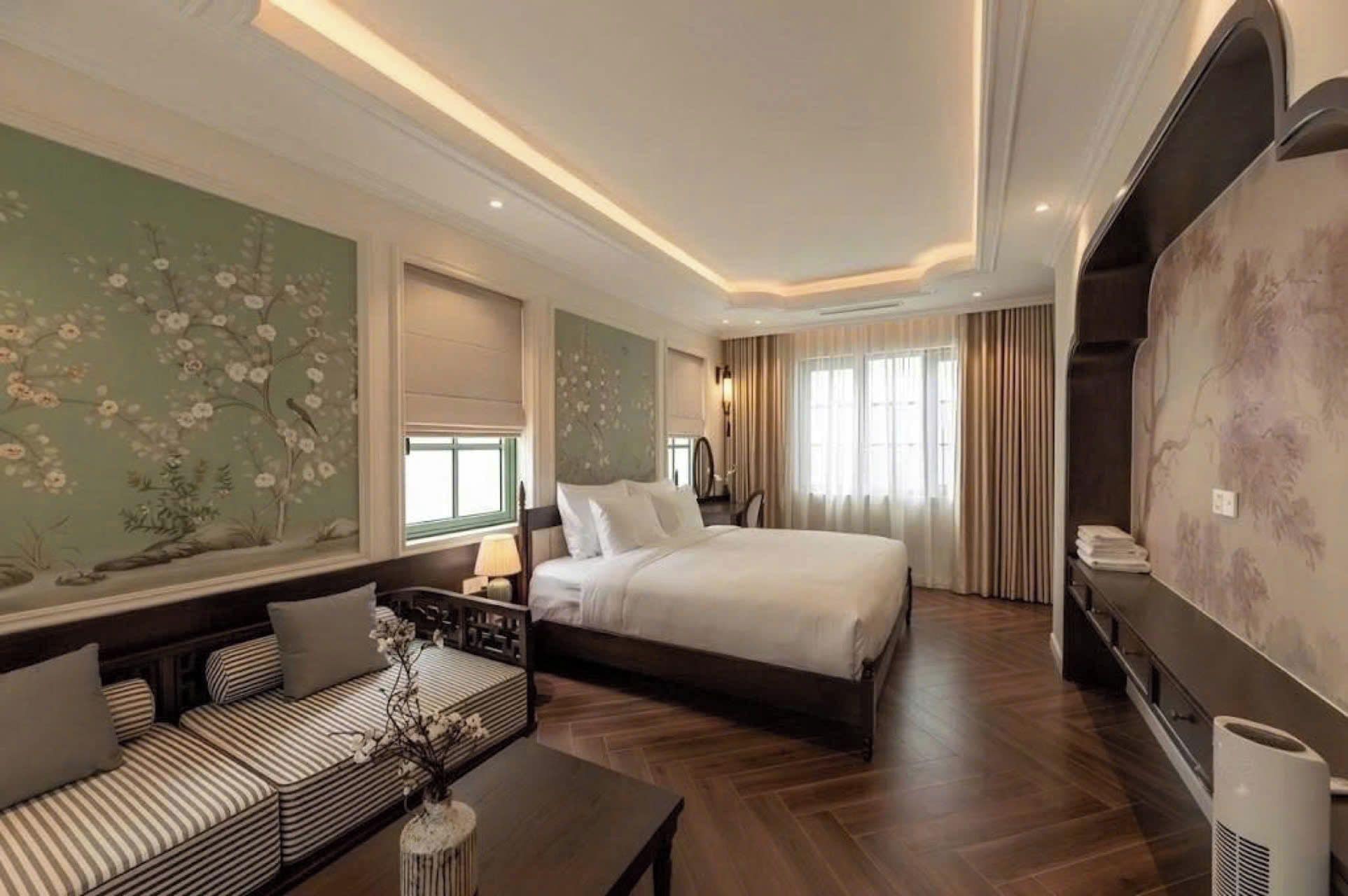 Una habitación de hotel con una cama grande, un sofá, un televisor y una pared decorativa.