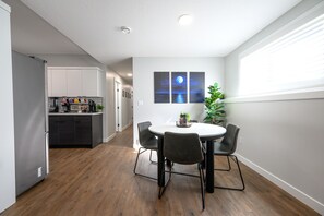 A modern kitchen with a built-in refrigerator, a coffee station, and a dining area with a round table and four chairs. - Cozy 2-bedroom, 1-bath Lower Duplex on North Side - Oasis Corporate Rentals (Grande Prairie)