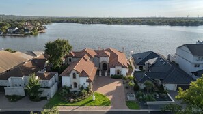 A residential area with houses near a lake, featuring a central building with a tiled roof and a driveway leading to it. - Villa at The Cape | Concierge Services (Horseshoe Bay)