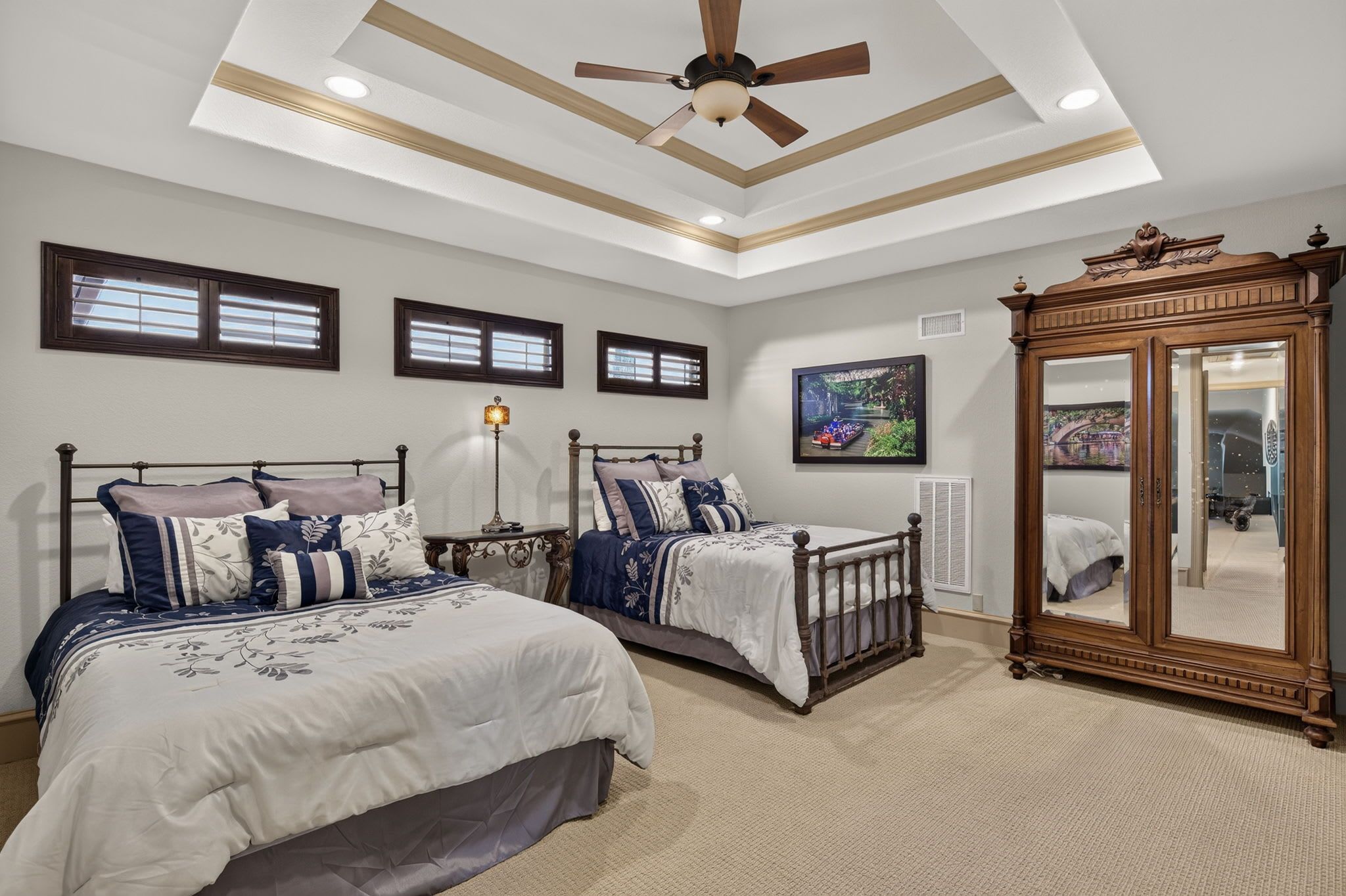 A bedroom with two beds, a ceiling fan, and a large mirror.