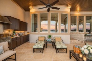 A spacious living area with a large window overlooking a scenic view, a ceiling fan, and a cozy seating arrangement. - Villa at The Cape | Concierge Services (Horseshoe Bay)