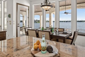 A dining area with a view of the water, a bottle of Topo Chico ginger beer, lemons, and a cheese grater on the counter. - Villa at The Cape | Concierge Services (Horseshoe Bay)