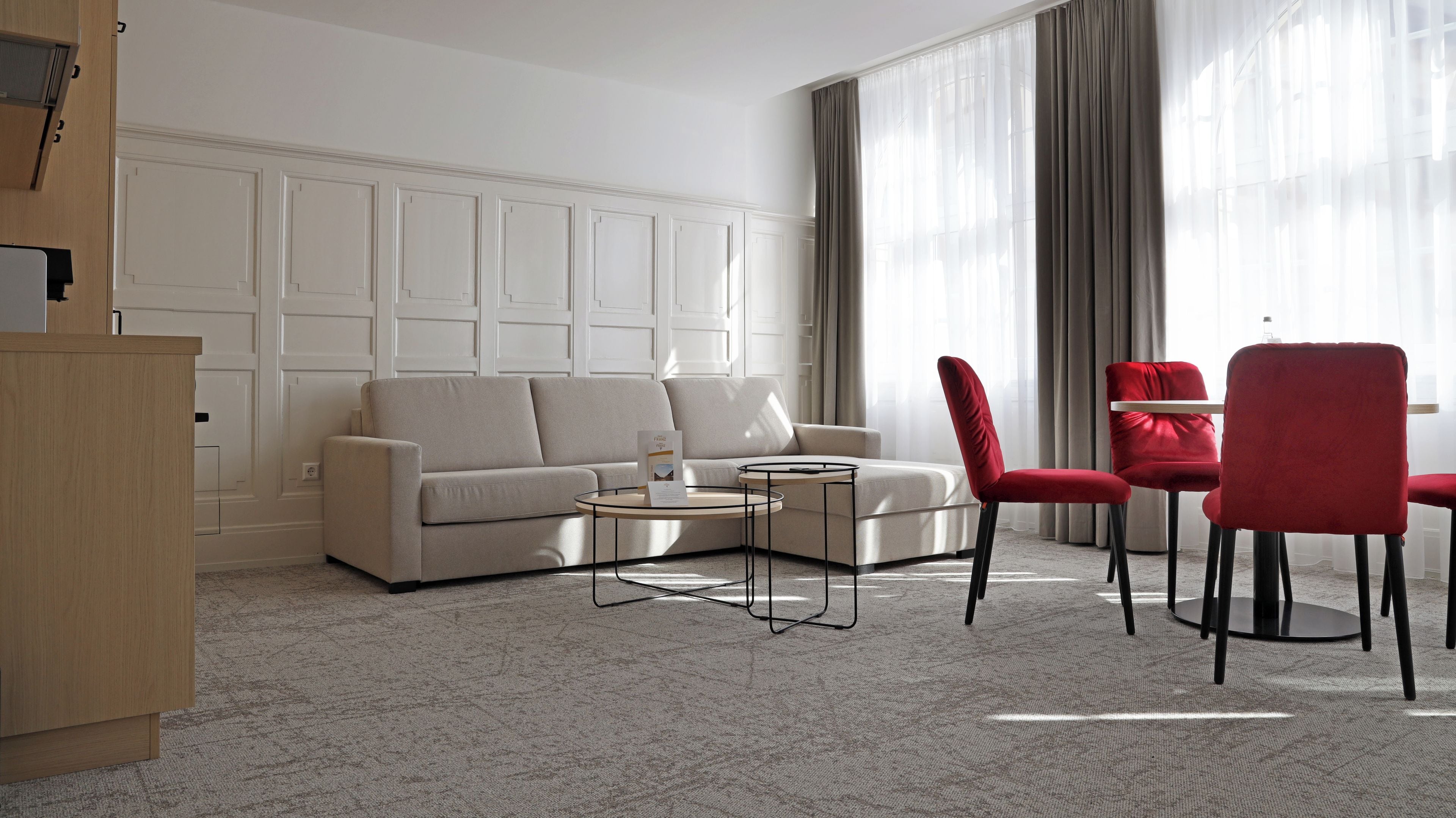 Una sala de estar moderna con un sofá beige, una mesita de centro y sillas rojas.