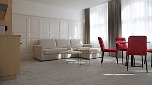A modern living room with a beige sofa, a coffee table, and red chairs.