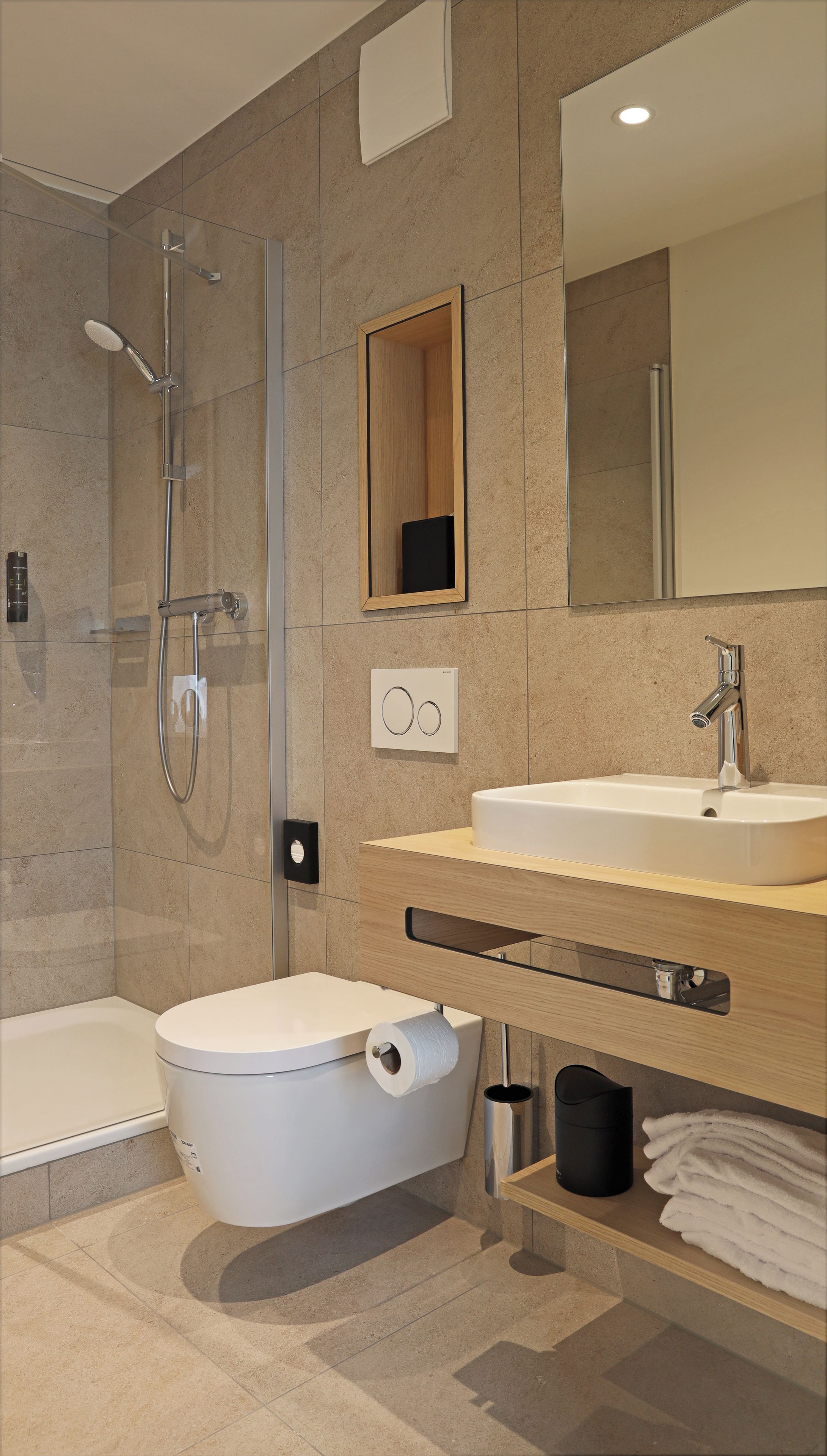 A modern bathroom with a glass-enclosed shower, a toilet, a bidet, a sink, and a mirror.