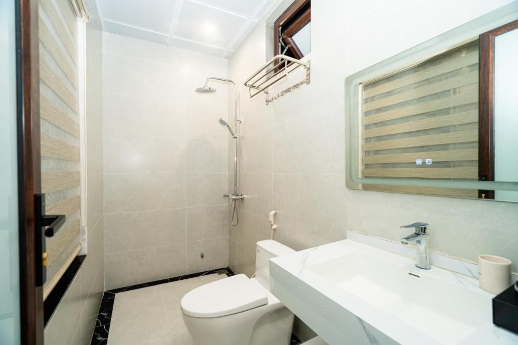 A bathroom with a toilet, a sink, a shower, and a mirror.