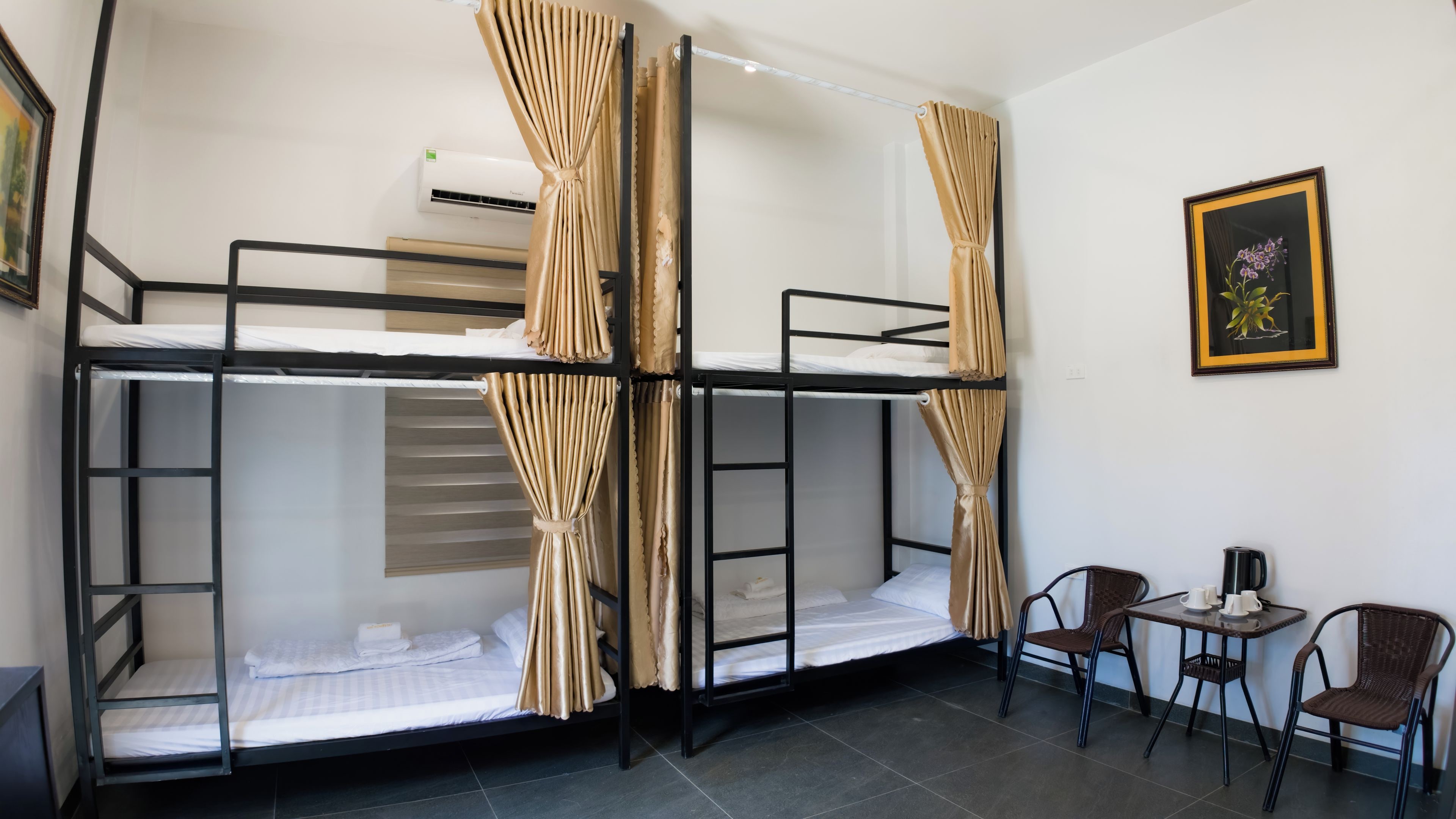 A bunk bed room with curtains, a small table with cups, and a framed picture on the wall.