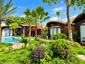 A resort with a swimming pool, thatched-roof cabins, and lush greenery. - Mai Homestay Ninh Binh (Nam Hoa Lu)