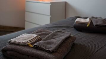 A bedroom with a bed, a bedside table with a lamp, a hanging light fixture, and a wall-mounted picture.