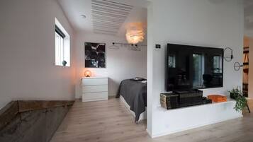 A modern bedroom with a bed, bedside table, and a TV mounted on the wall.