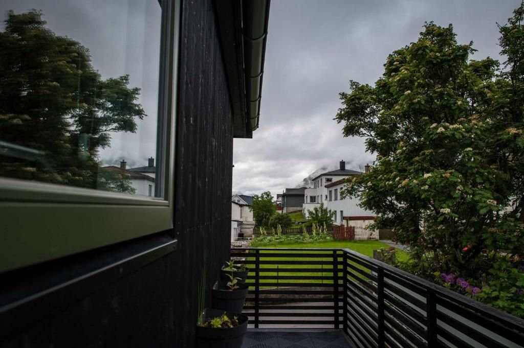 A balcony with a view of a residential area, including houses and trees.