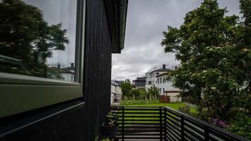 A balcony with a view of a residential area, including houses and trees.