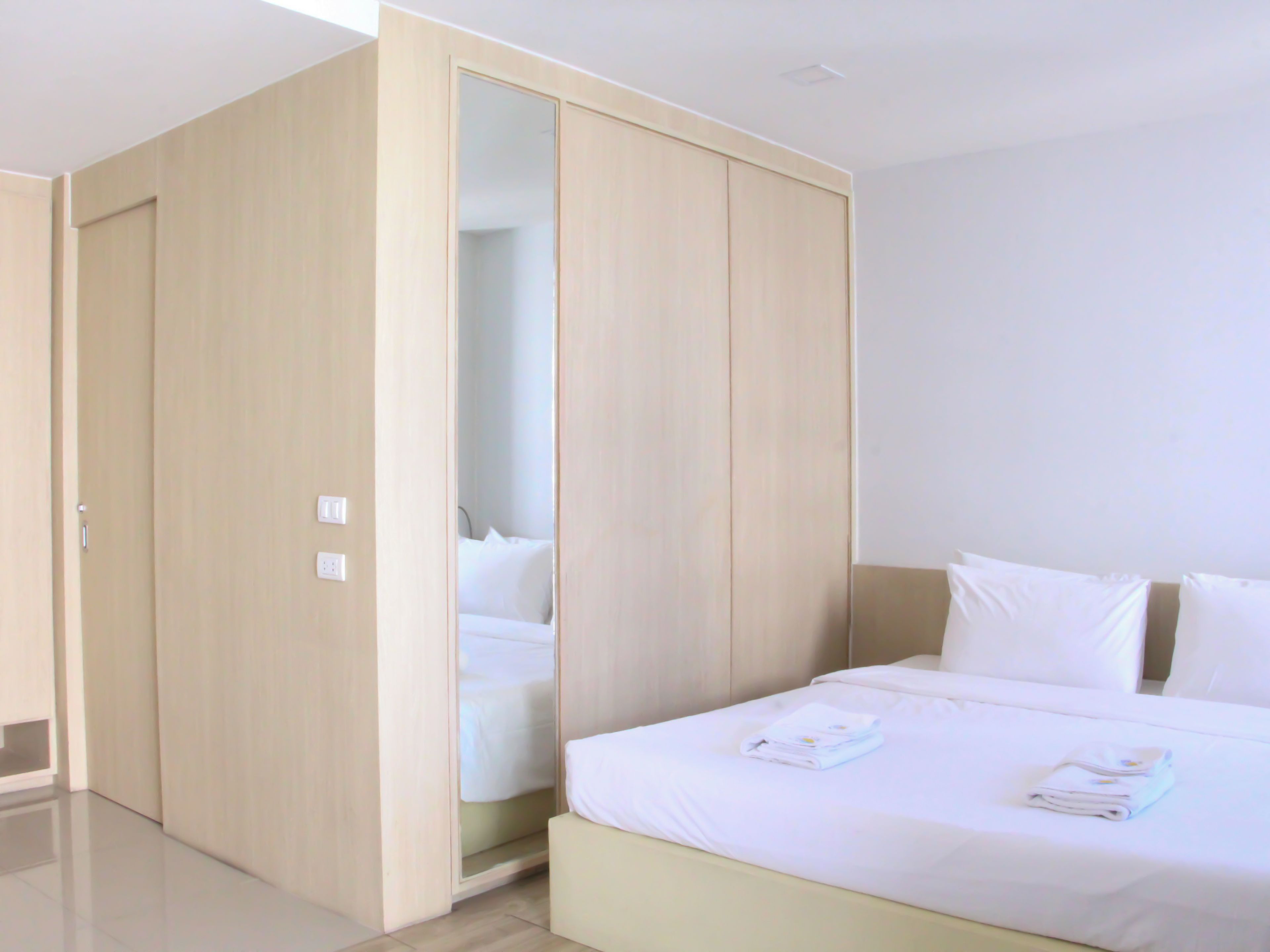 A hotel room with a bed, a wardrobe, and a mirror.