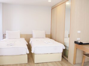 Habitación de hotel con dos camas, un armario de madera, un escritorio y un espejo.