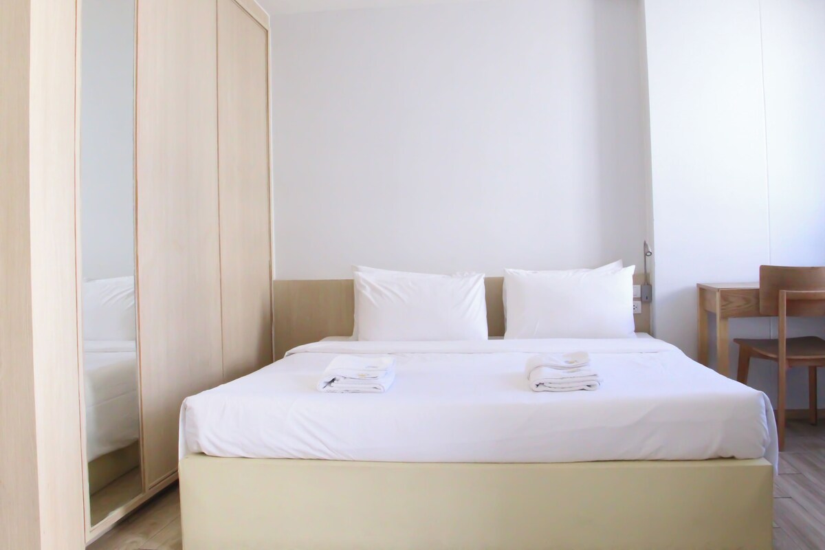 Een hotelkamer met een bed, een houten garderobe, een bureau en een stoel.