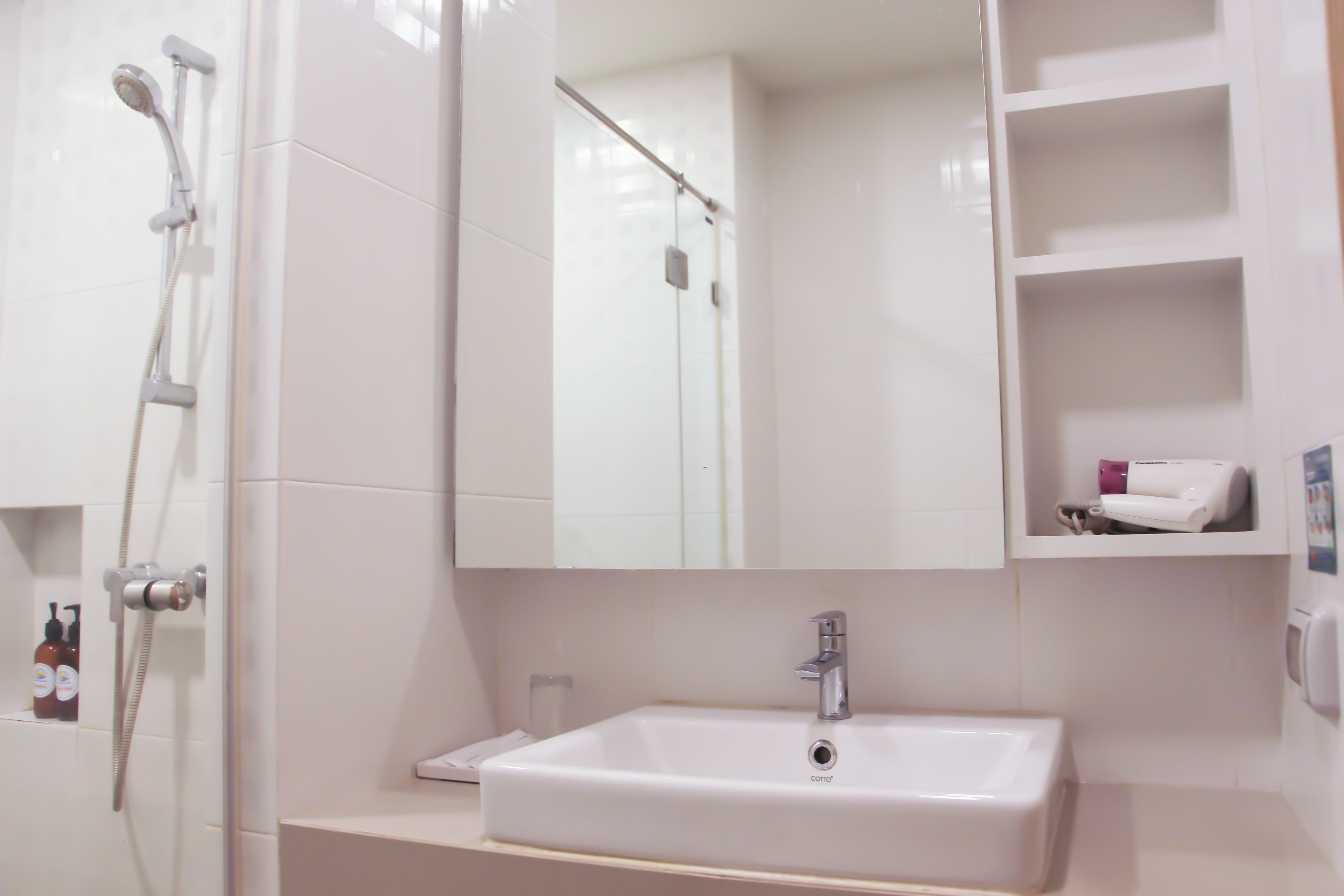 A bathroom with a white sink, a mirror, and a shower.