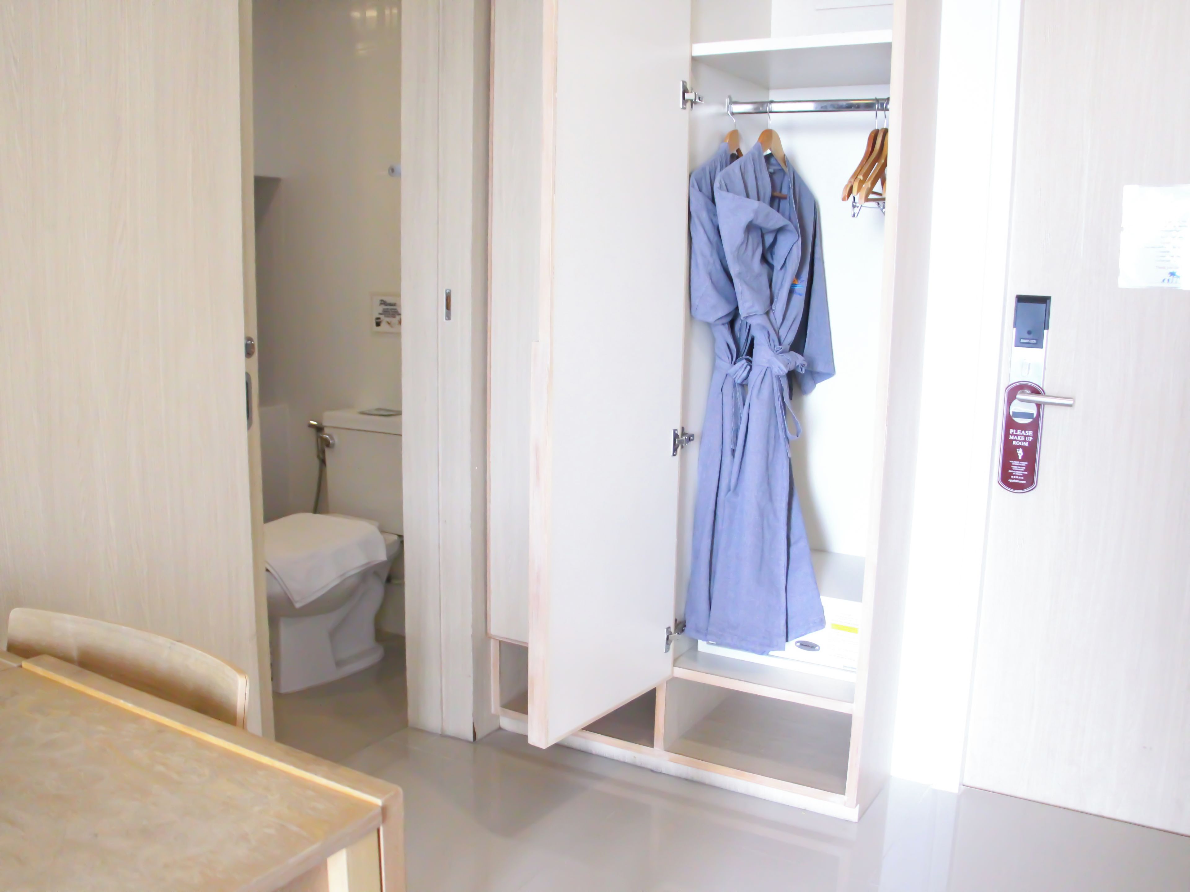 Une chambre d’hôtel avec salle de bain, un peignoir suspendu à un porte-manteau et une porte dotée d’une serrure de sécurité.