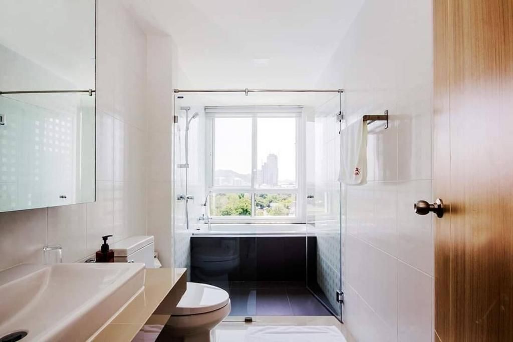 Un baño moderno con bañera, inodoro y lavabo. Cuenta con una ventana que ofrece luz natural y vistas al exterior.
