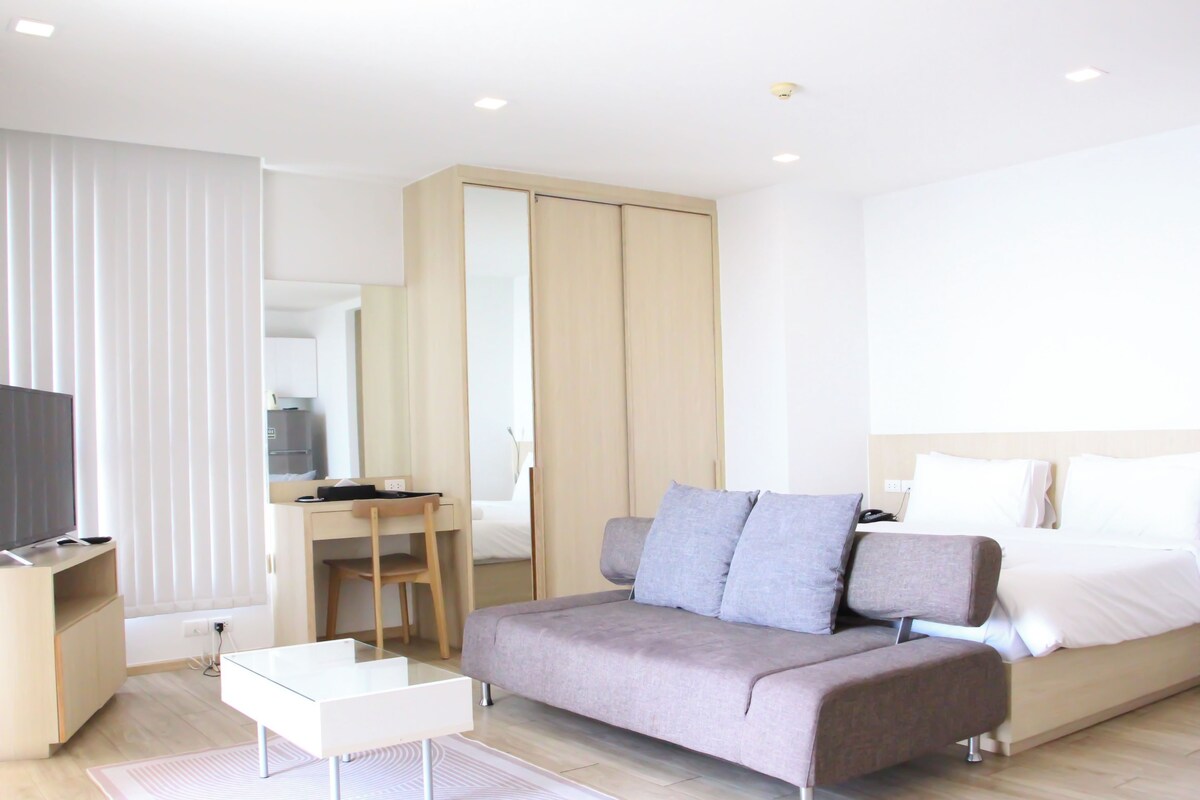 Een moderne hotelkamer met een bed, een slaapbank, een bureau en een televisie.