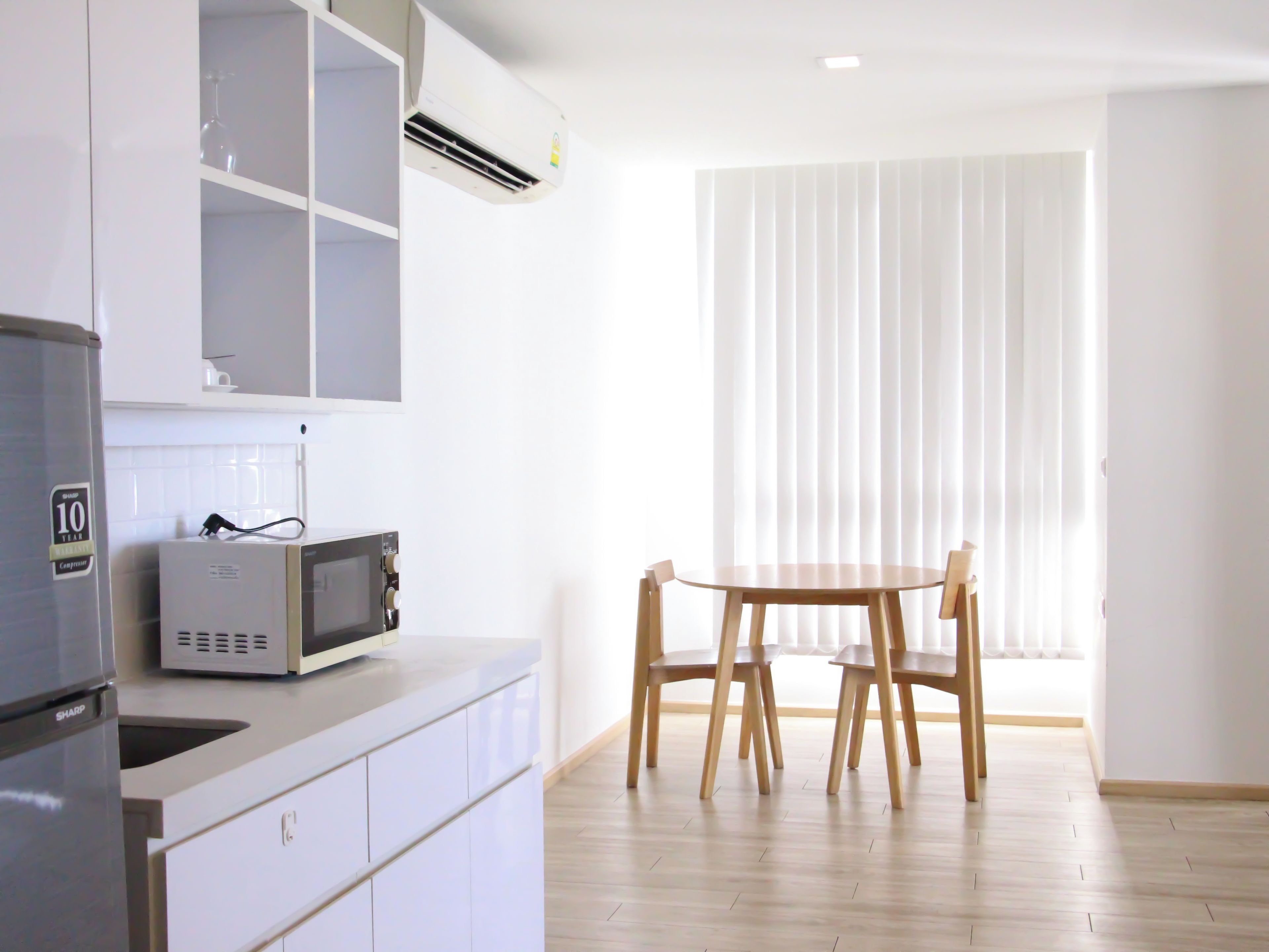 Una cocina con microondas, refrigerador y una mesa de comedor con sillas.