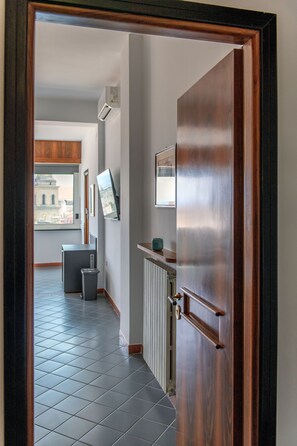 A hallway with a radiator, a trash bin, and a door leading to another room. - Toledo Skyview: Panoramic Penthouse in the Heart of Naples (Napoli)