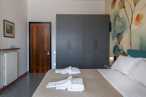 A bedroom with a bed, a wardrobe, a radiator, and a wall with a floral painting. - Toledo Skyview: Panoramic Penthouse in the Heart of Naples (Napoli)
