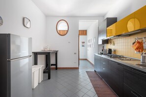A modern kitchen with a refrigerator, stove, and yellow cabinets. - Toledo Skyview: Panoramic Penthouse in the Heart of Naples (Napoli)