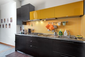 A modern kitchen with dark cabinetry, a yellow backsplash, and a stainless steel sink. - Toledo Skyview: Panoramic Penthouse in the Heart of Naples (Napoli)